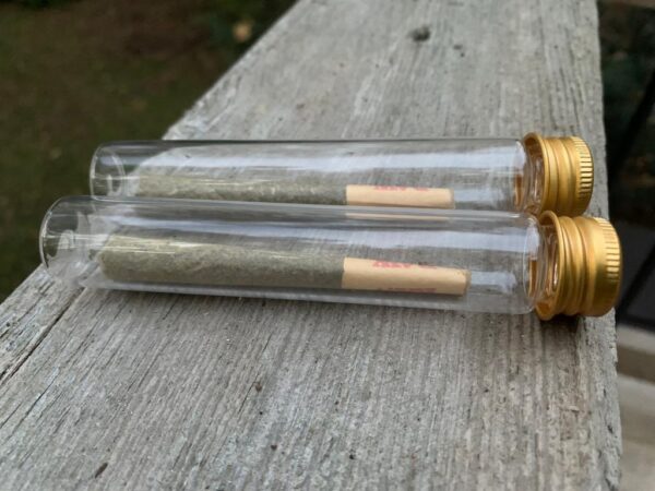 image of two pre-rolled joints on a glass tubes on a wooden surface